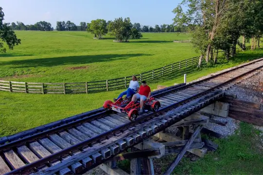 A mom and son journey over gentle bridges through open farmland.