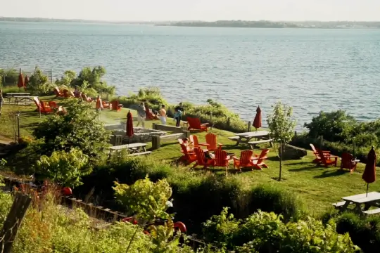 A couple pedals by the ocean smiling as the sun shines above. 