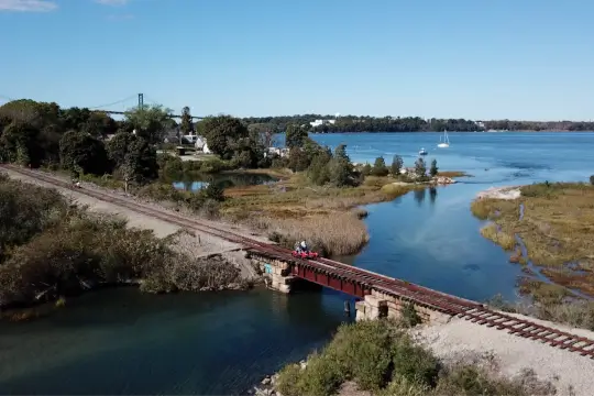 A railbike crosses into the Audubon Society Nature Preserve, as the Narragansett Bay flows underneath.