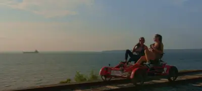Two housewives ride along the Rhode Island coastline at sunset, showcasing the shimmering water of the Narragansett Bay behind. 